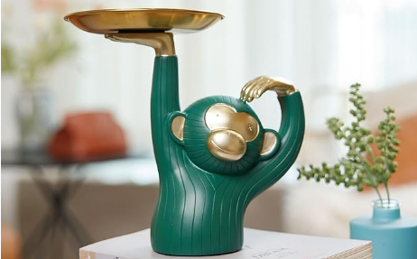 A green and gold monkey statue holding a gold snack tray