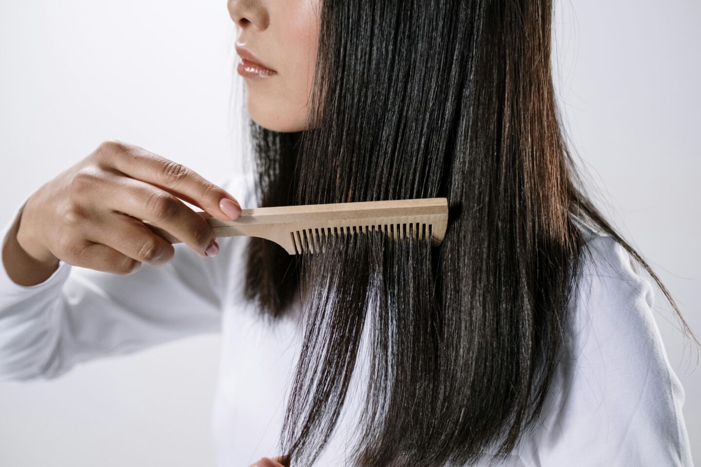 Image of a woman using a comb to brush her long hair.