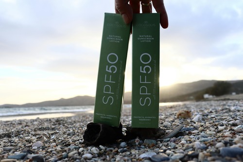 Two SPF 50 sunscreen bottles placed on a sandy beach