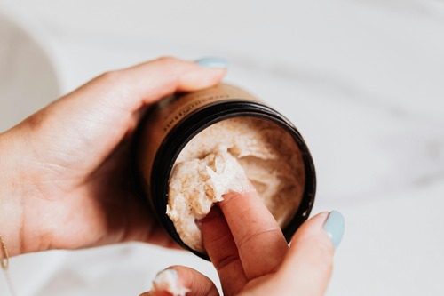 woman removing cream from brown jar