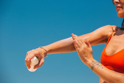 woman applying sunscreen on arm