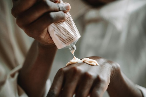 Squeezing out lotion from pink bottle onto back of hand