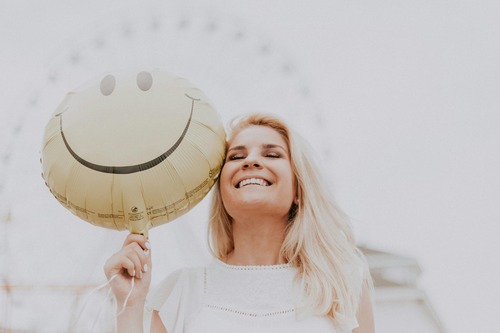  A woman joyfully holds a bright smiley face balloon